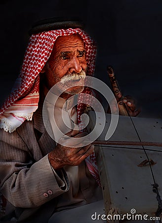 Little Petra, Jordan â€“ June 20, 2017:Old Bedouin man or Arab man in traditional outfit, playing his musical instrument . Editorial Stock Photo